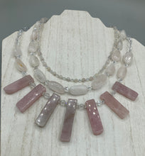 Load image into Gallery viewer, This impressive three-strand necklace is crafted from natural rose quartz stones and iridescent glass beads. The shortest strand is composed of petite round rose quartz beads, while the second strand contains an array of rectangular-shaped rose quartz and iridescent glass beads. The longest strand has long, vertical rectangular-shaped rose quartz beads, creating an elegant display across the chest. This necklace is an impressive, dynamic accessory. Necklace is 17: in length, can be adjusted to 19"