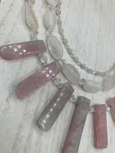 Load image into Gallery viewer, This impressive three-strand necklace is crafted from natural rose quartz stones and iridescent glass beads. The shortest strand is composed of petite round rose quartz beads, while the second strand contains an array of rectangular-shaped rose quartz and iridescent glass beads. The longest strand has long, vertical rectangular-shaped rose quartz beads, creating an elegant display across the chest. This necklace is an impressive, dynamic accessory. Necklace is 17: in length, can be adjusted to 19"