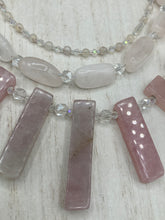 Load image into Gallery viewer, This impressive three-strand necklace is crafted from natural rose quartz stones and iridescent glass beads. The shortest strand is composed of petite round rose quartz beads, while the second strand contains an array of rectangular-shaped rose quartz and iridescent glass beads. The longest strand has long, vertical rectangular-shaped rose quartz beads, creating an elegant display across the chest. This necklace is an impressive, dynamic accessory. Necklace is 17: in length, can be adjusted to 19"