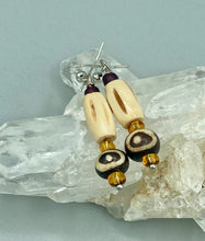 Load image into Gallery viewer, This set of earrings features a cylinder bone bead and round bone bead with eye design and a gold-tone glass bead. Neutral colors allow for versatile styling; the resulting look is sure to be unique.  Measurements: 1 1/2 ” in length