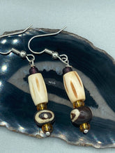 Load image into Gallery viewer, This set of earrings features a cylinder bone bead and round bone bead with eye design and a gold-tone glass bead. Neutral colors allow for versatile styling; the resulting look is sure to be unique.  Measurements: 1 1/2 ” in length