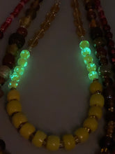 Load image into Gallery viewer, This necklace consists of three strands with a multitude of shades ranging from red to orange, gold, and amber, providing a captivating visual combination. Crafted with a combination of glass, ceramic and metal beads, this eye-catching piece of jewelry radiates power and strength. Measurements: Necklace is 16” in length, can be adjusted up to 17 1/2"