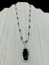 Load image into Gallery viewer, This dainty necklace is full of black and silver shimmery glass beads. A length black oval shaped glass bead hangs low to add length to this necklace.  It's the perfect necklace to add a little elegance to any outfit. Will go with any outfit, dress it up or down, this necklace will complete any look. This beauty is a must-have, add it to your jewelry collection.  Measurements: Necklace is 15 1/2” adjustable up to 18"- pendant is 1 1/2” Height