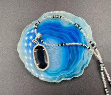 Load image into Gallery viewer, This dainty necklace is full of black and silver shimmery glass beads. A length black oval shaped glass bead hangs low to add length to this necklace.  It's the perfect necklace to add a little elegance to any outfit. Will go with any outfit, dress it up or down, this necklace will complete any look. This beauty is a must-have, add it to your jewelry collection.  Measurements: Necklace is 15 1/2” adjustable up to 18"- pendant is 1 1/2” Height