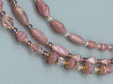 Load image into Gallery viewer, This three-strand beaded necklace is crafted with iridescent dusty rose glass, along with white, gold, pink, and iridescent purple beads for an eclectic mix of colors, tones, and textures. Perfect for any occasion, this gorgeous statement piece will add the finishing touch to your look. Measurements: Necklace is 17” in length, can be adjusted up to 19"