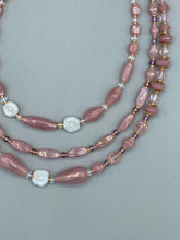 Load image into Gallery viewer, This three-strand beaded necklace is crafted with iridescent dusty rose glass, along with white, gold, pink, and iridescent purple beads for an eclectic mix of colors, tones, and textures. Perfect for any occasion, this gorgeous statement piece will add the finishing touch to your look. Measurements: Necklace is 17” in length, can be adjusted up to 19"
