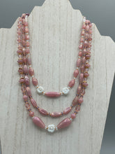 Load image into Gallery viewer, This three-strand beaded necklace is crafted with iridescent dusty rose glass, along with white, gold, pink, and iridescent purple beads for an eclectic mix of colors, tones, and textures. Perfect for any occasion, this gorgeous statement piece will add the finishing touch to your look. Measurements: Necklace is 17” in length, can be adjusted up to 19"