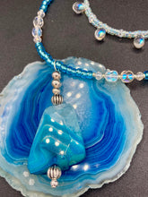 Load image into Gallery viewer, This exquisite necklace features a vibrant Sea Blue Agate Natural Stone Pendant and two strands of multi-colored glass beaded necklace. An adjustable collar-style strand contains small, light blue beads and lots of iridescent double-hole beads for shimmer and sparkle. The longer strand features larger blue glass beads interspersed with clear and silver beads for a sophisticated, draped look. It's finished with a set of dainty matching earrings for a complete look. Necklace is 14”adjustable up to 18"