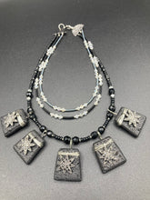 Load image into Gallery viewer, This eye-catching large trapezoid-shaped black lava stone wired pendant offers a lovely star-shaped charm design which gives the look of a night sky. Constructed of 3 strands, this statement piece exudes sophistication and charm. With matching earrings included, it is ideal for adding to your jewelry collection. Measurements: Necklace is is 15 1/2” adjustable up to 18"