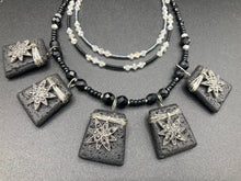Load image into Gallery viewer, This eye-catching large trapezoid-shaped black lava stone wired pendant offers a lovely star-shaped charm design which gives the look of a night sky. Constructed of 3 strands, this statement piece exudes sophistication and charm. With matching earrings included, it is ideal for adding to your jewelry collection. Measurements: Necklace is is 15 1/2” adjustable up to 18"