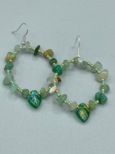 Load image into Gallery viewer, Natural aventurine stone chips, turquoise, and gold glass beads are strung together to form these stylish hoop earrings. The dark green pressed glass leaf charm complements the design, creating an iridescent, shimmery finish with subtle hues of gold, purple, blue, and pink. Measurements: 2" length
