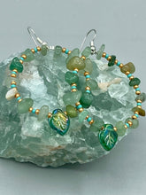 Load image into Gallery viewer, Natural aventurine stone chips, turquoise, and gold glass beads are strung together to form these stylish hoop earrings. The dark green pressed glass leaf charm complements the design, creating an iridescent, shimmery finish with subtle hues of gold, purple, blue, and pink. Measurements: 2" length