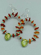 Load image into Gallery viewer, These Amber Stone Chip Beaded Hoop Earrings feature turquoise and gold glass beads, and a light green glass leaf charm with an iridescent shimmer finish with hints of gold, purple, blue, and pink. Measurements: 2" length