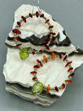 Load image into Gallery viewer, These Amber Stone Chip Beaded Hoop Earrings feature turquoise and gold glass beads, and a light green glass leaf charm with an iridescent shimmer finish with hints of gold, purple, blue, and pink. Measurements: 2" length