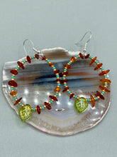 Load image into Gallery viewer, These Amber Stone Chip Beaded Hoop Earrings feature turquoise and gold glass beads, and a light green glass leaf charm with an iridescent shimmer finish with hints of gold, purple, blue, and pink. Measurements: 2" length