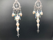 Load image into Gallery viewer, Large Chandelier Style Earrings Howlite Skull Beads Silver Plated Crosses. Ultimate Chingona, Cabrona, Latina Chicana, Goth, Vampire Goth, Dark Witchy Style. You can dress these up or down, it will definitely give your outfit a unique look. Cascade of dangling skulls and crosses have plenty of fun movement.  Measurements: 4” in length