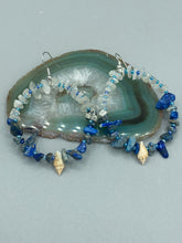 Load image into Gallery viewer, These earrings boast a beautiful combination of natural lapis and white moon stone chip stones, artfully inlaid with gold glass beads in a hoop formation. Dainty conch shells add a subtle touch of nature for a look that perfectly captures the beach vibes of summer. An ideal choice to complement any style. Measurements: 2 1/4" length