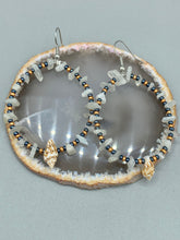 Load image into Gallery viewer, Dainty conch shells and natural white moon stone chips, these dark silver and gold glass beaded hoop earrings are the perfect accessory for any nature-loving, beach-themed outfit. Their versatility allows them to easily complement any outfit. Measurements: 2 1/4" length
