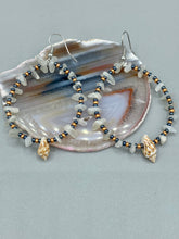 Load image into Gallery viewer, Dainty conch shells and natural white moon stone chips, these dark silver and gold glass beaded hoop earrings are the perfect accessory for any nature-loving, beach-themed outfit. Their versatility allows them to easily complement any outfit. Measurements: 2 1/4" length