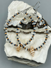 Load image into Gallery viewer, Dainty conch shells and natural white moon stone chips, these dark silver and gold glass beaded hoop earrings are the perfect accessory for any nature-loving, beach-themed outfit. Their versatility allows them to easily complement any outfit. Measurements: 2 1/4" length