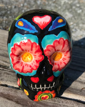 Load image into Gallery viewer, This Mini Day of the Dead Black Ceramic Sugar Skull is a stunning, nature-inspired piece of hand painted art. Featuring elements from a photography I took of a flower floating in a fountain at Grounds for Sculpture, this unique work of art is ideal for honoring memories of those who have passed. Its beautiful mausoleum, statues, and stained glass elements make it the perfect choice for any special occasion. Measurements: H 2 3/4” x W 2” x D 2”