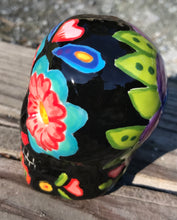 Load image into Gallery viewer, This Mini Day of the Dead Black Ceramic Sugar Skull is a stunning, nature-inspired piece of hand painted art. Featuring elements from a photography I took of a flower floating in a fountain at Grounds for Sculpture, this unique work of art is ideal for honoring memories of those who have passed. Its beautiful mausoleum, statues, and stained glass elements make it the perfect choice for any special occasion. Measurements: H 2 3/4” x W 2” x D 2”