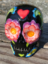 Load image into Gallery viewer, This hand-painted ceramic skull art is an homage to the traditional Mexican Day of the Dead. The inspiration for the skull's exquisite detail was taken from a beautiful flower photographed at the United States Botanic Garden - a whimsical surprise of small flowers floating in water. Bring La Muerte Calavera de Ofrenda, or 'skull of offering', into your home for a captivating reminder of Mexican tradition. H 2 3/4” x W 2” x D 2”