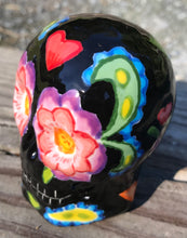 Load image into Gallery viewer, This hand-painted ceramic skull art is an homage to the traditional Mexican Day of the Dead. The inspiration for the skull's exquisite detail was taken from a beautiful flower photographed at the United States Botanic Garden - a whimsical surprise of small flowers floating in water. Bring La Muerte Calavera de Ofrenda, or 'skull of offering', into your home for a captivating reminder of Mexican tradition. H 2 3/4” x W 2” x D 2”