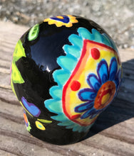 Load image into Gallery viewer, This black ceramic sugar skull, inspired by nature, is adorned with hand-painted floral motifs, hearts, leaves and colorful accents. Its vibrant style and intricate details create a stunning Dia De Los Muertos calavera. Perfect for creating ofrendas to celebrate the Day of the Dead. Measurements: H 2 3/4” x W 2” x D 2”