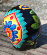 Load image into Gallery viewer, This black ceramic sugar skull, inspired by nature, is adorned with hand-painted floral motifs, hearts, leaves and colorful accents. Its vibrant style and intricate details create a stunning Dia De Los Muertos calavera. Perfect for creating ofrendas to celebrate the Day of the Dead. Measurements: H 2 3/4” x W 2” x D 2”