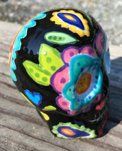 Load image into Gallery viewer, This black ceramic sugar skull, inspired by nature, is adorned with hand-painted floral motifs, hearts, leaves and colorful accents. Its vibrant style and intricate details create a stunning Dia De Los Muertos calavera. Perfect for creating ofrendas to celebrate the Day of the Dead. Measurements: H 2 3/4” x W 2” x D 2”