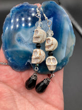 Load image into Gallery viewer, This luxurious design features two large howlite skull beads and a large black teardrop shaped glass bead; perfect for achieving a Chingona, Cabrona, Latina Chicana, Goth, Vampire Goth, Dark Witchy, La Bruja look. This statement jewelry will add a unique touch to any outfit.