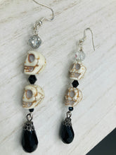 Load image into Gallery viewer, This luxurious design features two large howlite skull beads and a large black teardrop shaped glass bead; perfect for achieving a Chingona, Cabrona, Latina Chicana, Goth, Vampire Goth, Dark Witchy, La Bruja look. This statement jewelry will add a unique touch to any outfit.