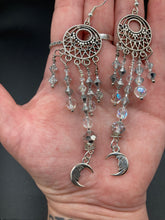 Load image into Gallery viewer, Whimsical Celestial Smiling Crescent Moons Large Chandelier Earrings. Five strands of beautiful clear iridescent glass beads and dangling smiling crescent moon charms. This is perfect for any outfit and will surely stand out. Measurements:  4” in length. Witchy, Whimsical, Goth, Luna Lovers, Crescent Smiling Moons