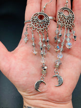 Load image into Gallery viewer, Whimsical Celestial Smiling Crescent Moons Large Chandelier Earrings. Five strands of beautiful clear iridescent glass beads and dangling smiling crescent moon charms. This is perfect for any outfit and will surely stand out. Measurements: 4” in length. Witchy, Whimsical, Goth, Luna Lovers, Crescent Smiling Moons