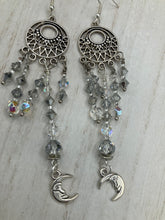 Load image into Gallery viewer, Whimsical Celestial Smiling Crescent Moons Large Chandelier Earrings. Five strands of beautiful clear iridescent glass beads and dangling smiling crescent moon charms. This is perfect for any outfit and will surely stand out. Measurements:  4” in length. Witchy, Whimsical, Goth, Luna Lovers, Crescent Smiling Moons