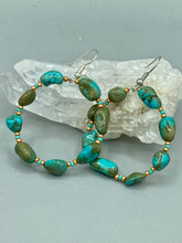 Load image into Gallery viewer, Our Blue-Green Magnesite Stone Beaded Hoop Earrings provide a nature-inspired look that is perfect for any boho-chic style. These earrings feature natural magnesite stone beads with small beads of turquoise and gold glass for subtle accent. Show off your bohemian look with these eye-catching hoops. Measurements: 2" length