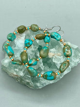 Load image into Gallery viewer, Our Blue-Green Magnesite Stone Beaded Hoop Earrings provide a nature-inspired look that is perfect for any boho-chic style. These earrings feature natural magnesite stone beads with small beads of turquoise and gold glass for subtle accent. Show off your bohemian look with these eye-catching hoops. Measurements: 2" length