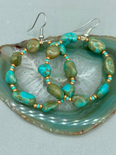 Load image into Gallery viewer, Our Blue-Green Magnesite Stone Beaded Hoop Earrings provide a nature-inspired look that is perfect for any boho-chic style. These earrings feature natural magnesite stone beads with small beads of turquoise and gold glass for subtle accent. Show off your bohemian look with these eye-catching hoops. Measurements: 2" length