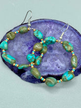 Load image into Gallery viewer, Our Blue-Green Magnesite Stone Beaded Hoop Earrings provide a nature-inspired look that is perfect for any boho-chic style. These earrings feature natural magnesite stone beads with small beads of turquoise and gold glass for subtle accent. Show off your bohemian look with these eye-catching hoops. Measurements: 2" length