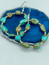 Load image into Gallery viewer, Our Blue-Green Magnesite Stone Beaded Hoop Earrings provide a nature-inspired look that is perfect for any boho-chic style. These earrings feature natural magnesite stone beads with small beads of turquoise and gold glass for subtle accent. Show off your bohemian look with these eye-catching hoops. Measurements: 2" length