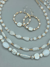 Load image into Gallery viewer, These white floral glass beaded hoop earrings bring a bohemian, shabby-chic, and nature-inspired vibe to any look. Crafted with small iridescent, gold, and white glass beads, they are the perfect accessory for any fashionista who loves beach vibes, summer elements, and chic boho styles. Measurements: 2 1/4" length