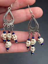 Load image into Gallery viewer, Stunning Cascade of Tiny Howlite Skull Dark Purple Glass Bead Chandelier Earrings. Chicana Chingona Chola Style Jewelry. Beautiful elegant set of teardrop earrings has an eerie beautiful vibe. Tiny dangling howlite skull beads. You can dress these up or down, it will definitely give your outfit a unique look. Versatile looks from Witchy, Goth, Dia De Los Muertos, Vampire Goth. Measurements: 2” in length