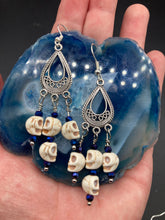 Load image into Gallery viewer, Stunning Cascade of Tiny Howlite Skull Dark Purple Glass Bead Chandelier Earrings. Chicana Chingona Chola Style Jewelry. Beautiful elegant set of teardrop earrings has an eerie beautiful vibe. Tiny dangling howlite skull beads. You can dress these up or down, it will definitely give your outfit a unique look. Versatile looks from Witchy, Goth, Dia De Los Muertos, Vampire Goth. Measurements: 2” in length