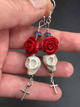 Load image into Gallery viewer, Frida Kahlo Inspired Earrings, Chicana Chingona Chola Style Jewelry. Howlite Skull Bead With Red Quartize Rose Beads. Beautifully and elegant set of earrings captures Frida Kahlo's signature floral crown on her head, dangling silver plated cross gives these earrings some movement. These are a beautiful piece of jewelry to wear for inspiration or a great Dia De Los Muertos jewelry piece. You can dress these up or down, it will definitely give your outfit a unique look. 2 ” in length