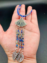 Load image into Gallery viewer, Triangle Illuminati Silver Plated Pendant With Blue And Silver Color Glass Bead Adjustable Necklace.  Mysterious and unique necklace has a very whimsical vibe with a dash of mystery. Contains 5 beaded strands with intricate leaf charms that create movement. This unique look will complete any outfit. Witchy, Gothic, Illuminati, Mysterious versatile style, bold elegant piece of jewelry.  Measurements: Necklace is 16 1/2” adjustable up to 19" in length - pendant is 4” Height with bail