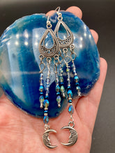 Load image into Gallery viewer, These three-strand chandelier style earrings offer an ornate and eye-catching look with their whimsical blue celestial charm accents adorned with smiling crescent moon designs. Perfect for creating a fairy princess, witchy, or boho aesthetic, they provide plenty of movement and can easily be added to any jewelry collection.  Measurements: 3 1/2” in length