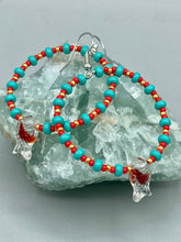 Load image into Gallery viewer, This eye-catching set of earrings features intricately detailed koi fish glass beads, accompanied by smaller teal, red, and gold-hued glass beads. With their bold and vibrant colors, they make a striking statement. Measurements: 2 1/4” in length