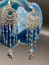 Load image into Gallery viewer, These intricate moroccan blue Inspired large chandelier earrings boast five strands of blue and iridescent glass beads of various hues, including silver and gold. Additionally, two small dark blue glass beads with a silver leaf add a touch of dimension and motion. The perfect addition to any Fairy Princess or whimsical aesthetic.  Measurements: 4” in length