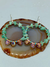 Load image into Gallery viewer, These Aventurine Stone Chip Beaded Hoop Earrings feature natural aventurine stone chips, turquoise, and gold glass beads. The amber-tone pressed glass leaf charm has an iridescent shimmer finish, with subtle accents of gold, purple, blue, and pink. Measurements: 2" length